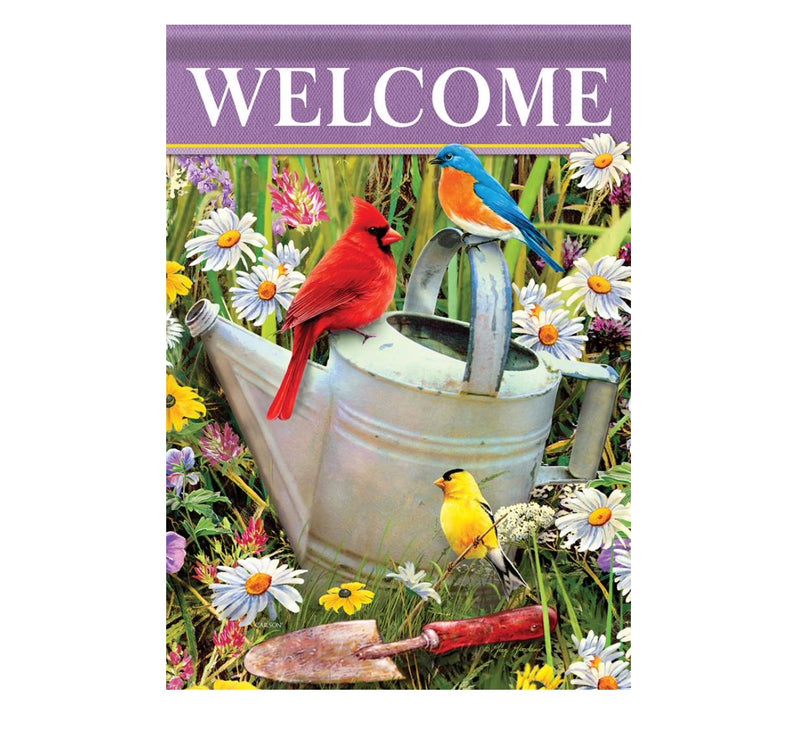 A vibrant garden flag scene with a "WELCOME" message at the top. Three colorful birds sit on or near a metal watering can surrounded by blooming flowers, including daisies. A garden trowel is placed in the foreground amidst the lively foliage, adding to the welcoming atmosphere. This is the Flag Songbirds Meet from MyHomeDecor.ca.