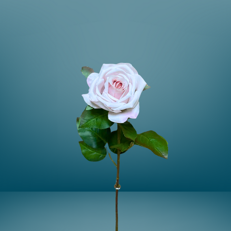 A delicate pink rose with lush green leaves is set against a blue gradient background. This 27" Fresh Touch Vienna Rose Spray - Blush by MyHomeDecor.ca's petals are soft and slightly curled, showcasing its full bloom, while the stem extends downward, displaying a few small thorns in this exquisite floral arrangement.