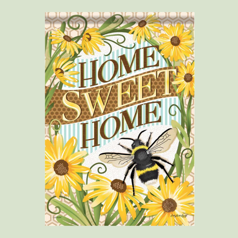 An illustrated poster with the text "HOME SWEET HOME" in bold, golden-brown letters. Around the text, there are bright yellow sunflowers and a large, detailed bee on the bottom right. The background features a subtle honeycomb pattern and light blue stripes. The product is called Flag Home Sweet Home Bee by MyHomeDecor.ca.