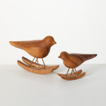 Two Small Bird on Rocker - Brown sculptures of different sizes from MyHomeDecor.ca are shown side by side. Each Small Bird on Rocker - Brown features a smooth, polished finish and stands on metal legs attached to wooden rockers, evoking the look of rocking horses. The backdrop is a clean, white surface.