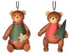 Two MyHomeDecor.ca Ornament - Green Teddy Bear ornaments are hanging side by side. The left bear, wearing a green sweater, is holding a star, while the right bear, in a red outfit, clutches a small Christmas tree ornament. Both bears have round ears, black eyes, and small smiles.