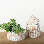 Two **Wide Cement Flower Pots - Two Tones** by **MyHomeDecor.ca** sit on a burlap surface, exuding Boho style. One pot holds a green leafy plant, while the other is empty and slightly tilted to lean against the first. These charming flower pots stand out beautifully against the plain white background.